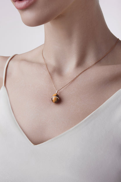Female model wearing Fabergé Heritage Forever Tigers Eye Pendant in 18k rose gold with diamonds. 