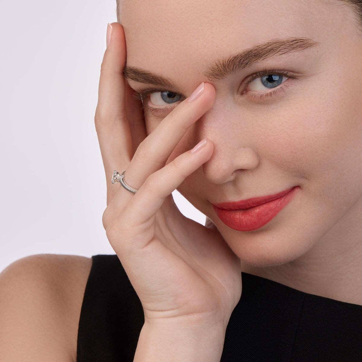 Model wearing a white gold diamond pavé ring with a central diamond stone, posed with hand partially covering the face against a neutral background.