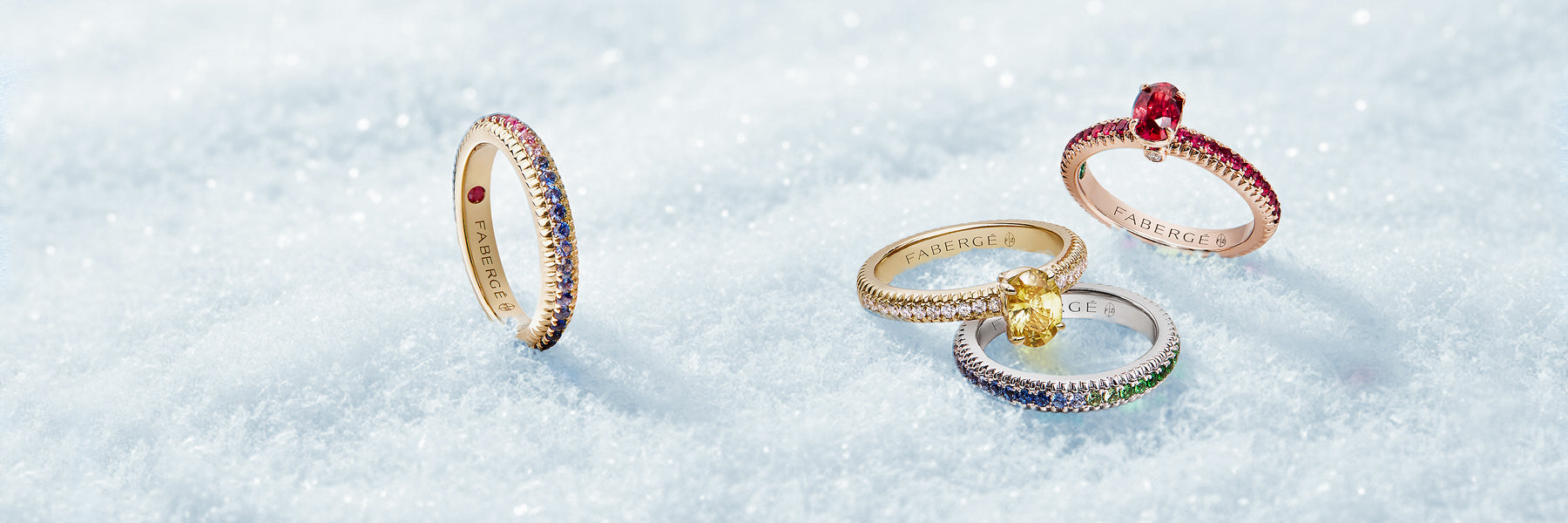 Four Fabergé rings in 18k gold on a textured white surface