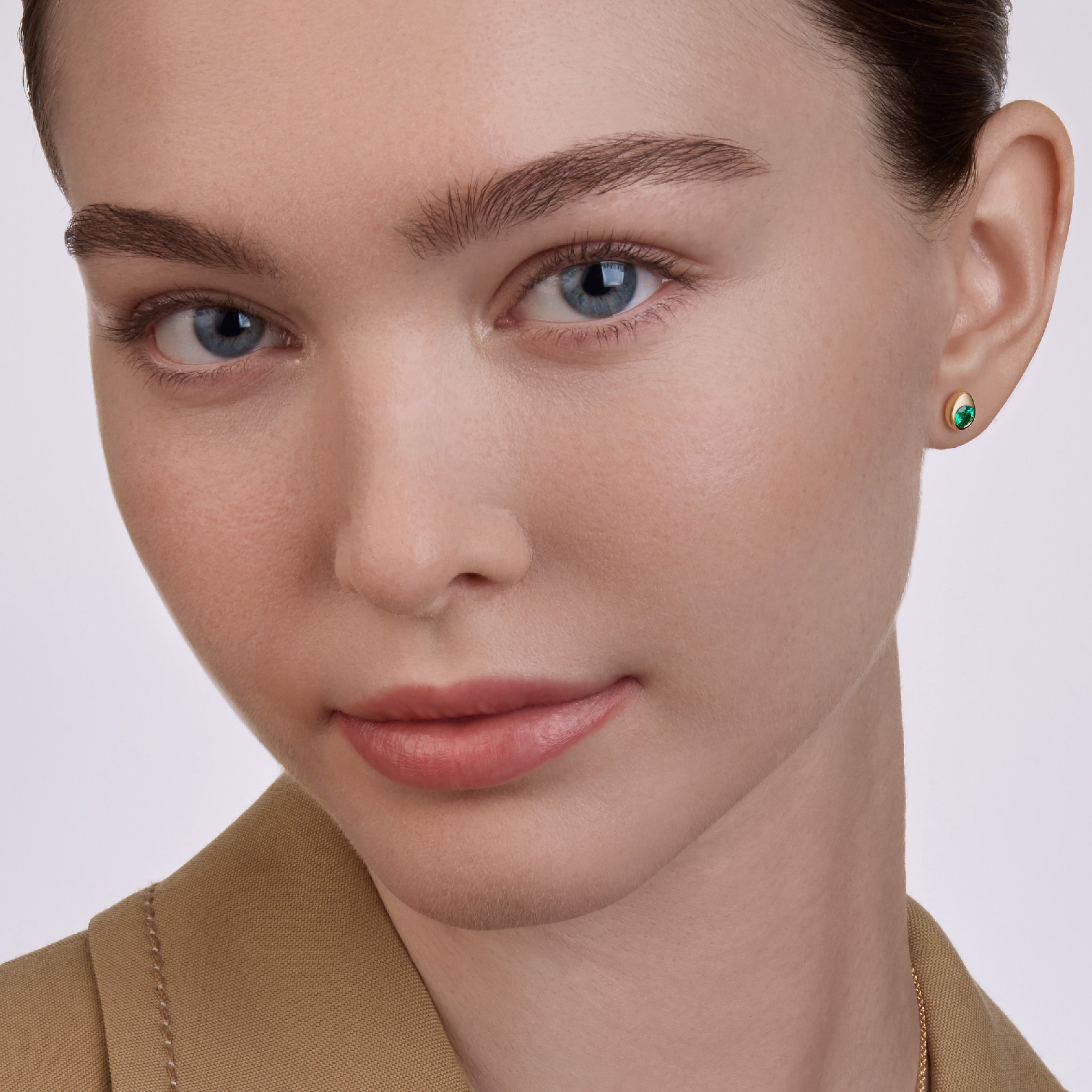 Model Image Close-up featuring Fabergé Code emerald stud earrings set in yellow gold