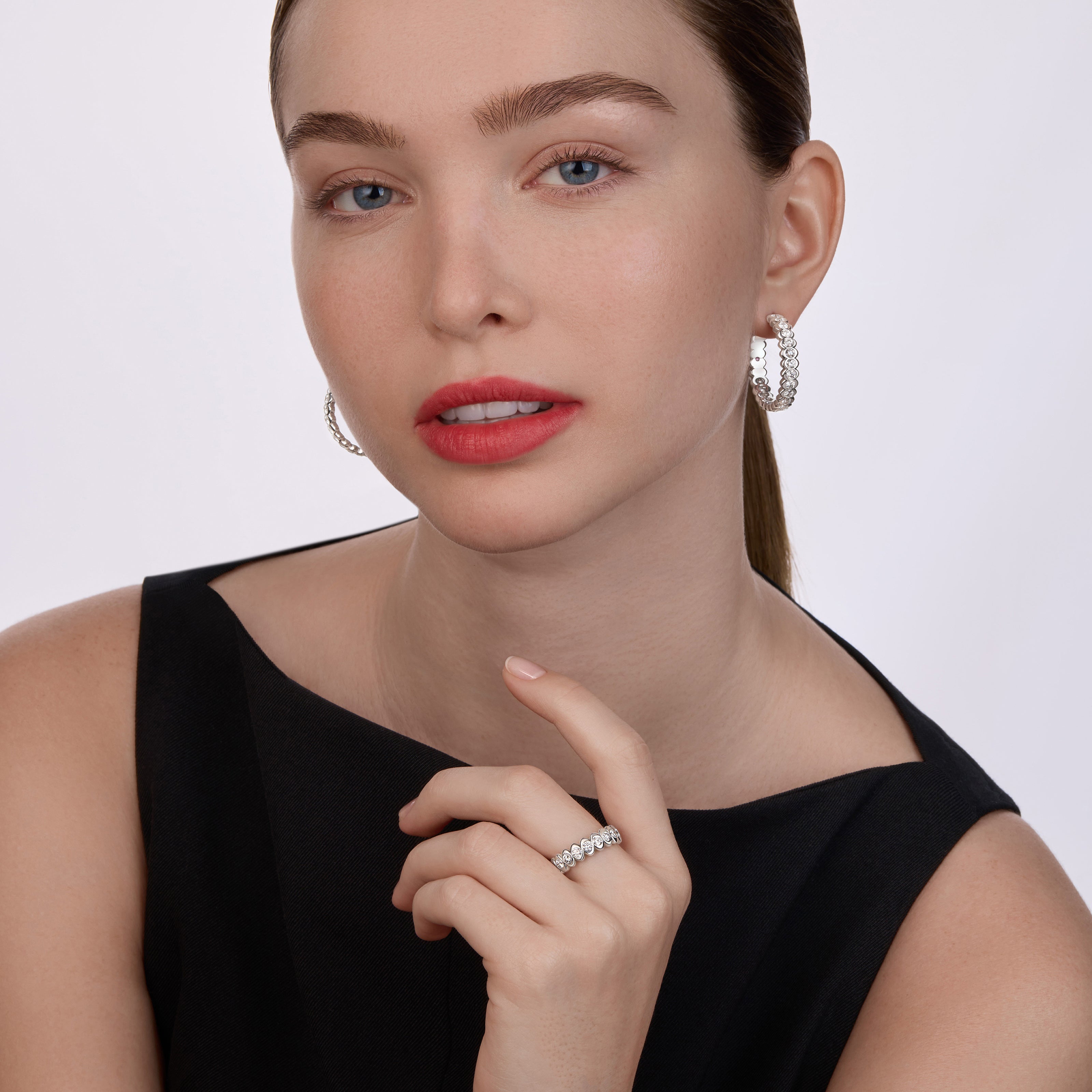Model wearing Fabergé Code diamond hoop earrings and matching diamond ring in white gold with contemporary geometric detailing.