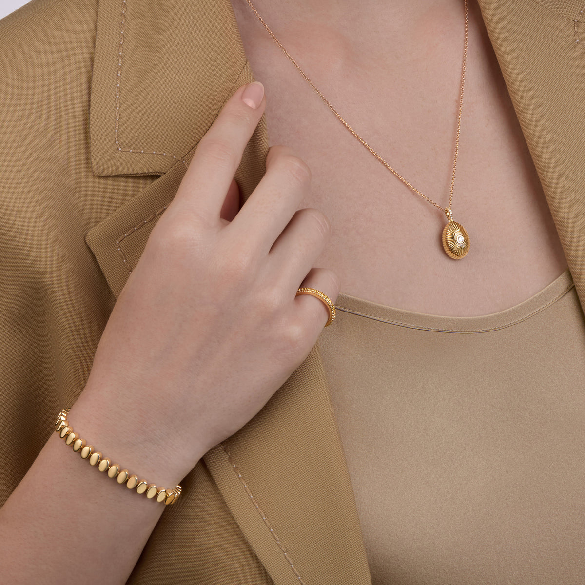 Close-up of Fabergé Heritage egg pendant necklace paired with Love Collection gemstone ring and a old code necklace
