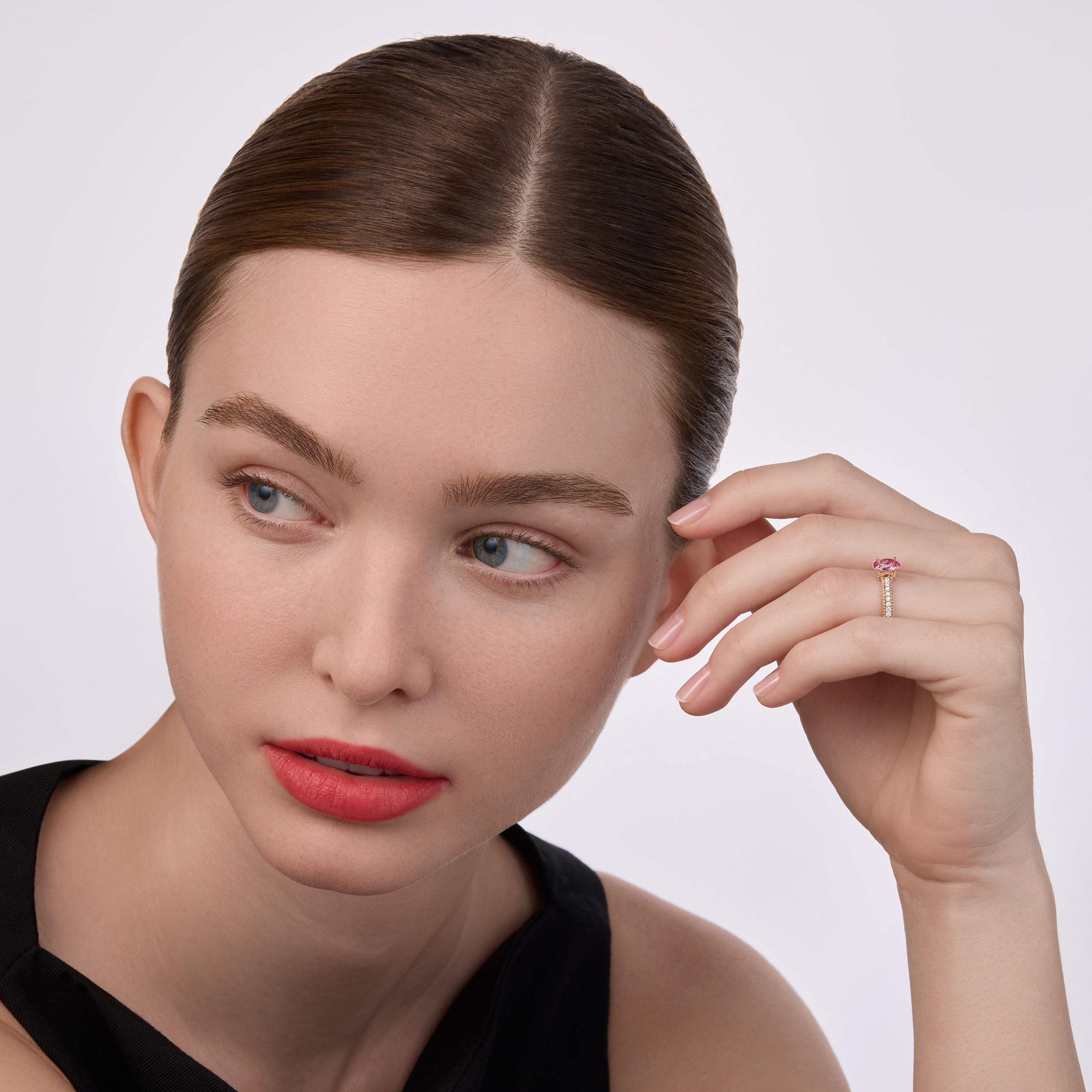 Model wearing a rose gold Fabergé ring with a pink gemstone centre stone and pavé-set diamonds, styled with a black dress.