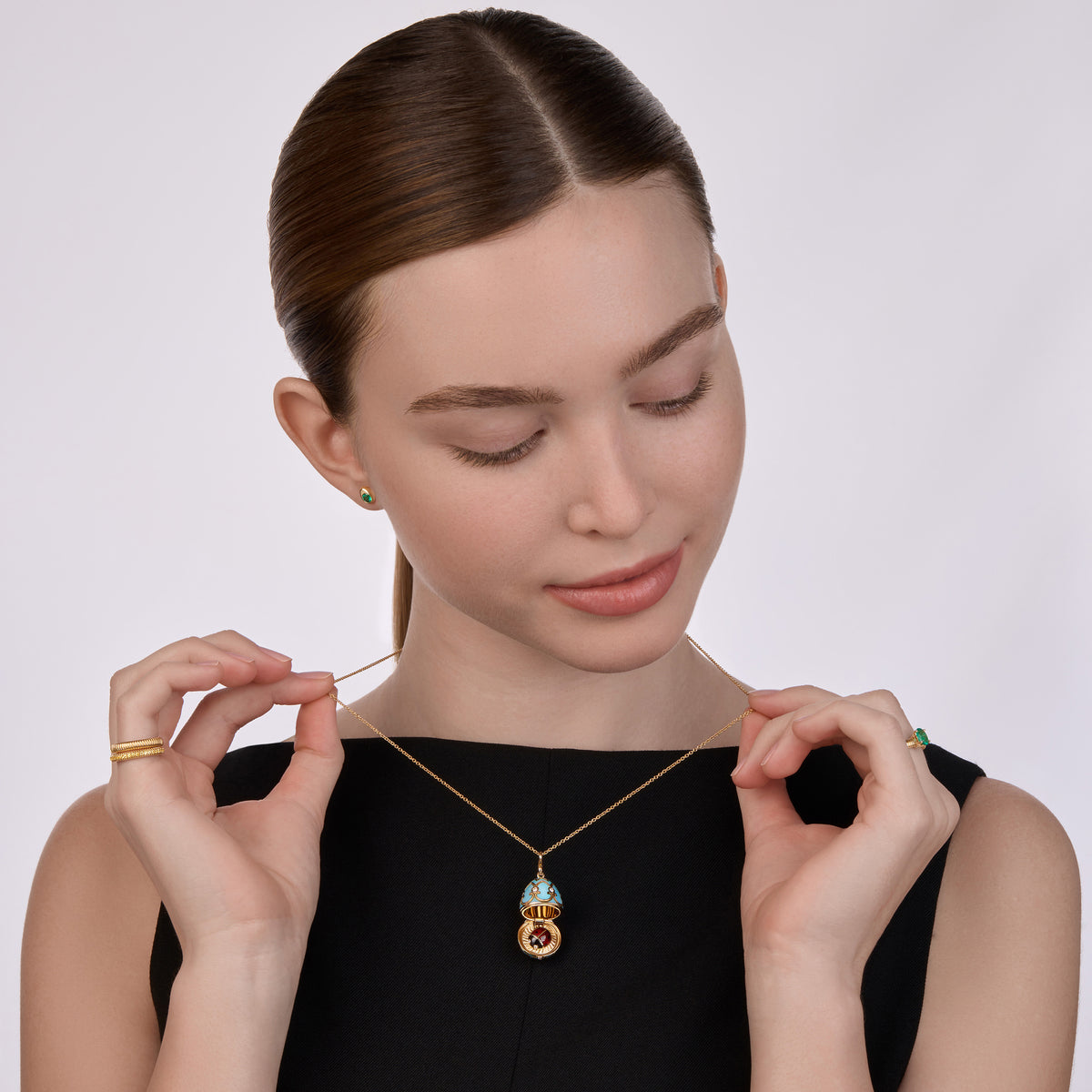 Model wearing the Fabergé Surprise Ladybird pendant necklace, paired with Code gold rings, emerald stud earrings, and a Love emerald ring in yellow gold.Model wearing the Fabergé Surprise Ladybird pendant necklace, paired with Code gold rings, emerald stud earrings, and a Love emerald ring in yellow gold.