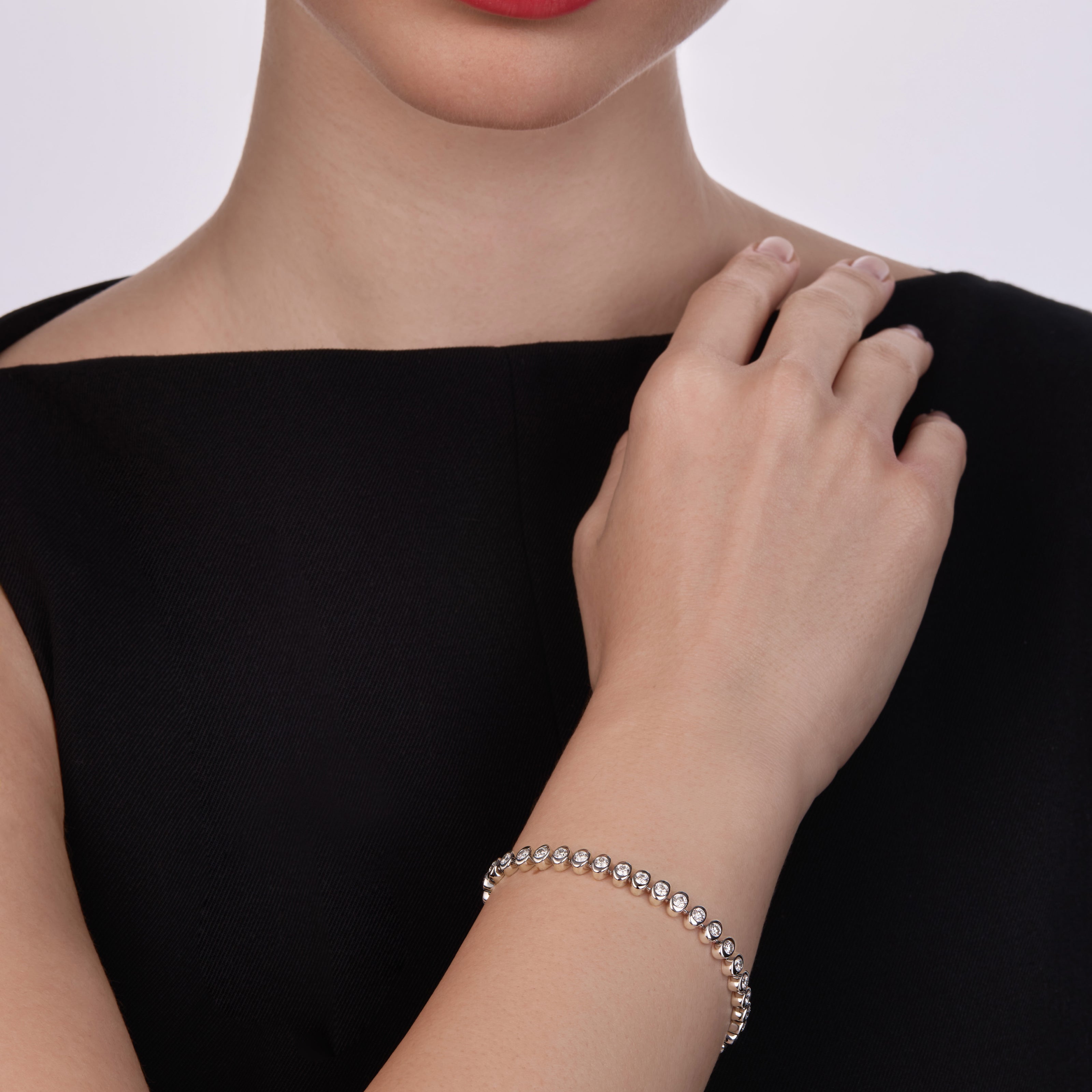 Woman wearing a Fabergé Platinum Diamond Tennis Bracelet on a plain background