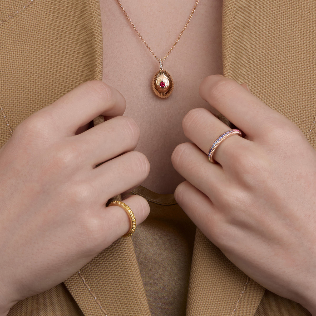 Close-up of Fabergé Heritage egg pendant necklace paired with Love Collection gemstone rings, featuring colourful pavé detailing in yellow and rose gold.